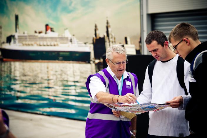 cruise liverpool ambassador giving instructions to two passengers looking at a map