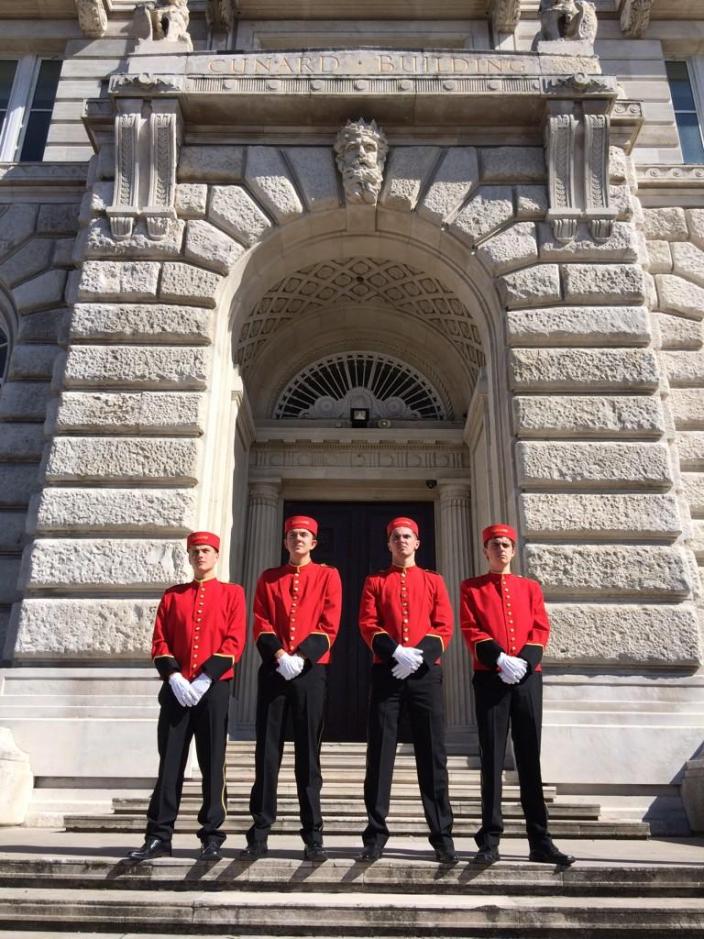 four bell boys standing outside the main doors to cunard building