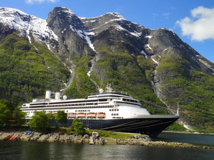 Fred Olsen cruise vessel on the water with a backgdrop of mountains and a blue sky