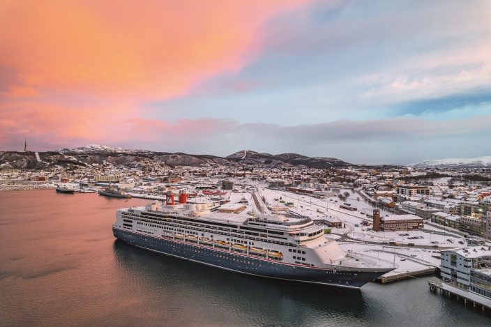 Borealis in Bodø, Norway against a pink and pale blue sky